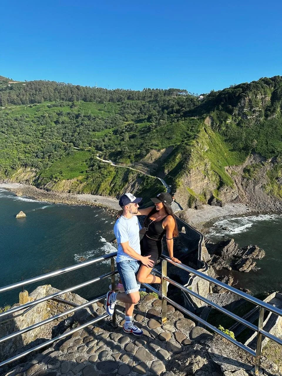 Catalina y David en la escalera de piedra que baja al mar en la costa vasca