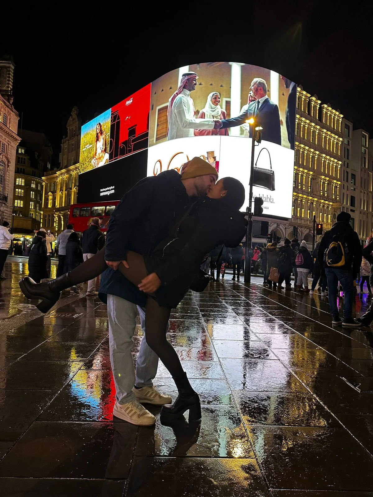 David levantando a Catalina en Piccadilly Circus, sobre el suelo mojado